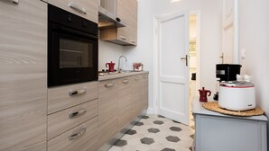 A modern kitchen with wooden cabinets, a black oven, and a coffee maker on the counter.