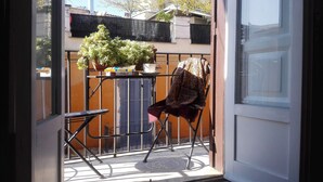 A balcony with a chair, a small table, and a potted plant.