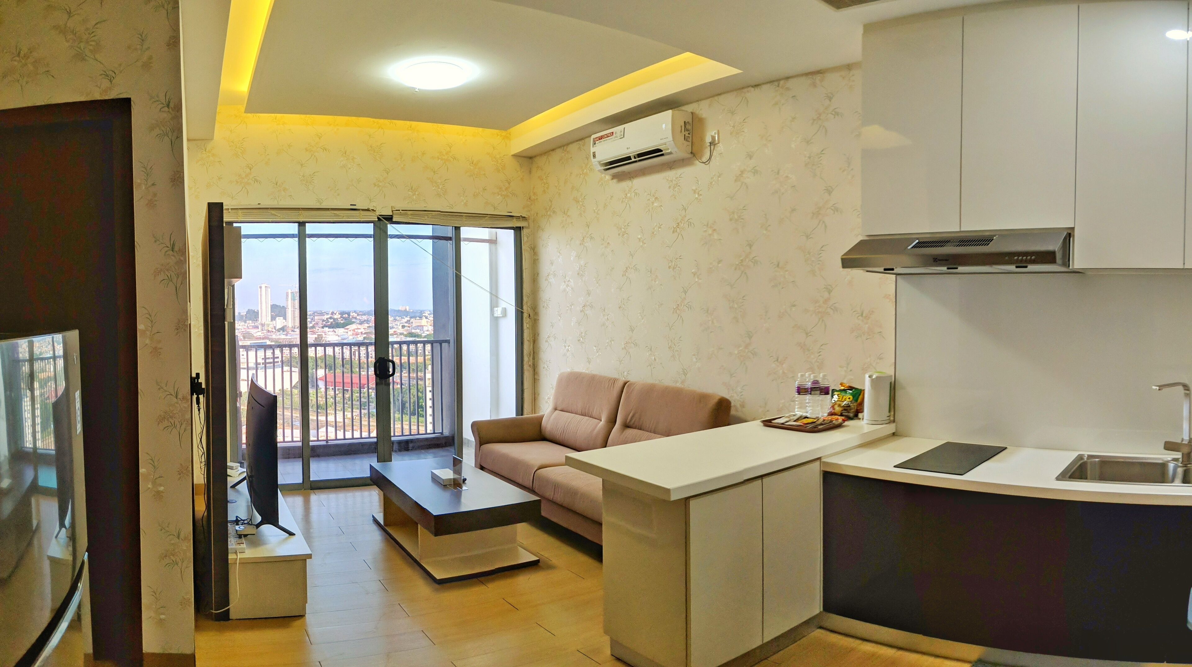 A modern apartment with a balcony, a kitchenette, and a sofa.