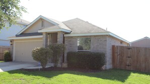 A single-story house with a garage, a brick exterior, and a wooden fence.