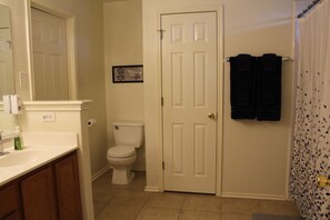 A bathroom with a toilet, sink, and a door leading to another room.