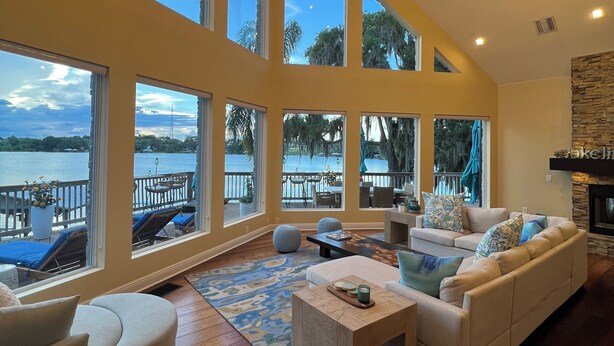 A spacious living room with a large sofa, a coffee table, and a view of the water through large windows.
