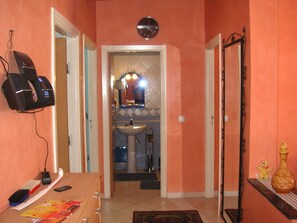 A hallway with a sink, mirror, and clock. There is a telephone and a small table with a vase and a teddy bear. - Concluded and quiet residential complex in the city center (Agadir)
