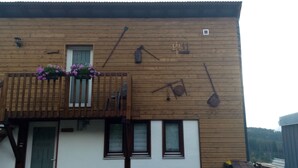 A wooden building with a balcony, a window, and a door.