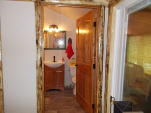 Une salle de bain avec une porte en bois, un lavabo, des toilettes et un miroir.