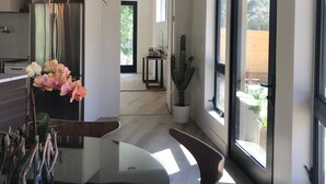 A modern kitchen with a glass dining table, wooden chairs, a unique light fixture, and a view of the outdoors. - OBSERVATION POINT- 2 Miles from main entrance to ZNP New Barrel Sauna by river (Springdale)