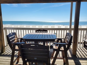 Una terraza de madera con una mesa y sillas que da a una playa.