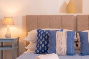 A bed with a headboard, a bedside table with a lamp, and a wall-mounted vase.