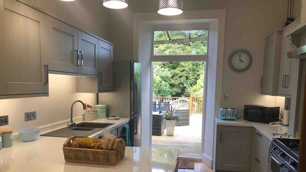 Una cocina moderna con una isla central, electrodomésticos integrados y vistas a un patio exterior.