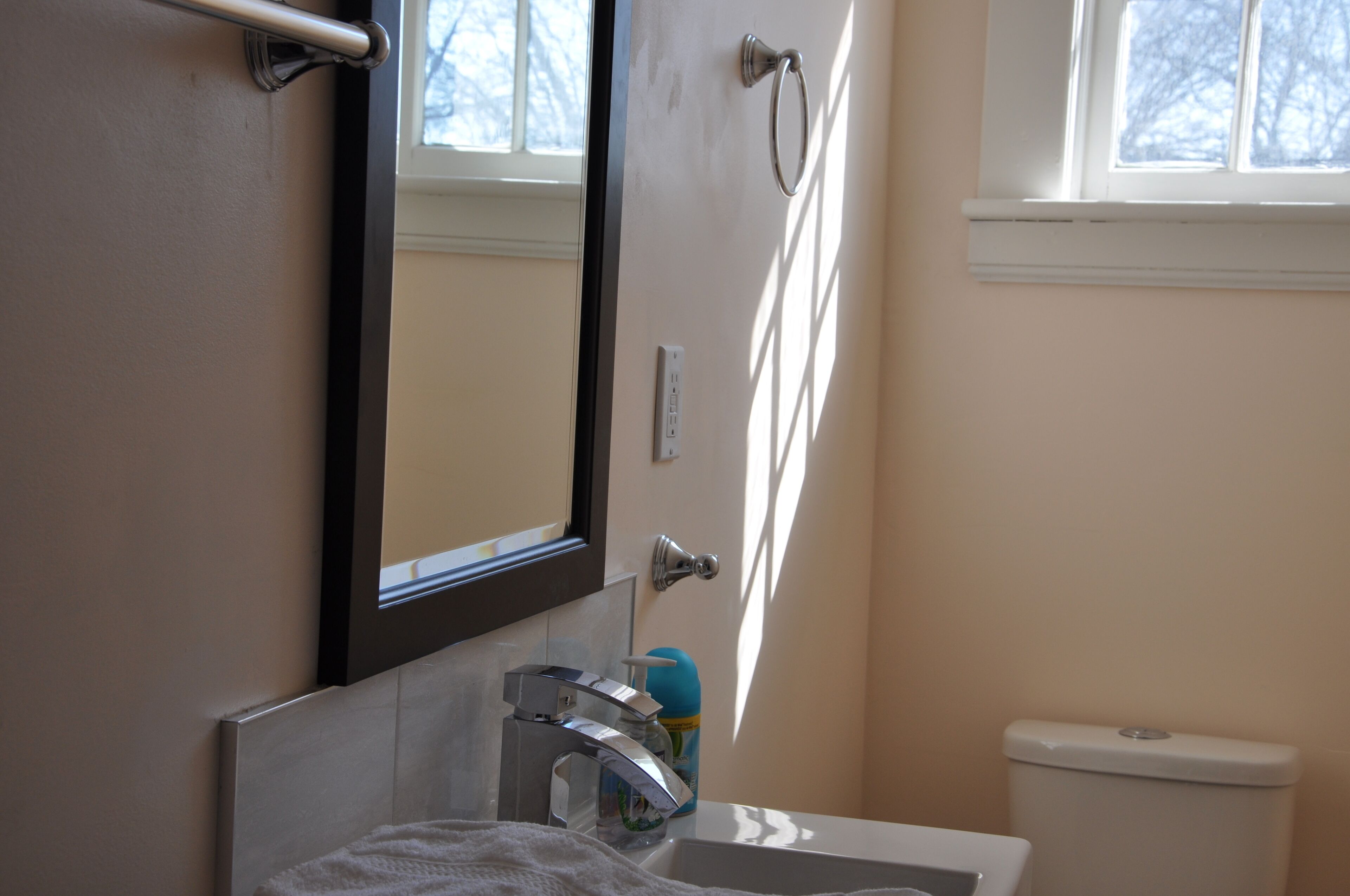 A bathroom with a toilet, sink, and mirror.