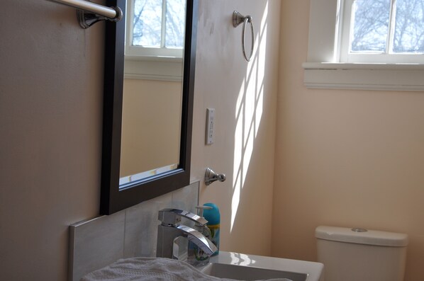 A bathroom with a toilet, sink, and mirror.