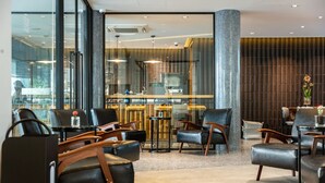 A modern interior with leather chairs, a bar area, and large windows. - Reno Hotel Bangkok (Bangkok)