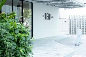A modern building exterior with a white facade, a glass entrance, and a metal fence. - Reno Hotel Bangkok (Bangkok)