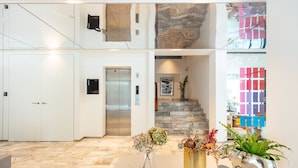 A modern hotel lobby with a marble floor, a reception desk, a staircase, and decorative vases. - Reno Hotel Bangkok (Bangkok)