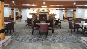 A spacious indoor area with a central fireplace, multiple seating arrangements, and a stone-tiled floor.
