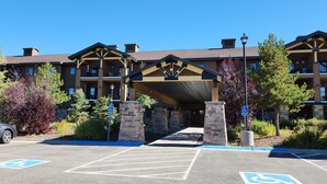 A hotel entrance with handicapped parking spaces, a covered walkway, and a stone pillar.