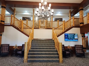 A grand staircase with wooden railings and a chandelier, leading to a second floor.