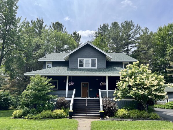 A two-story house with a dark gray exterior, white trim, and a front porch with steps leading to a door.