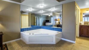 A bathroom with a large bathtub, a mirror, and a sink.