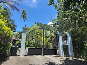 A gated entrance with a metal gate, a sign indicating private access, and lush greenery in the background.