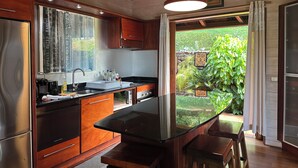 Une cuisine moderne dotée d’un grand îlot central, de meubles en bois et offrant une vue sur un jardin.