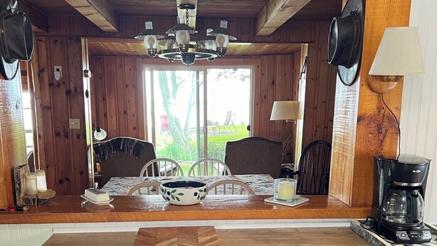 Une cuisine avec des meubles de rangement en bois, un plan de travail en bois, une table à manger avec des chaises et une machine à café.