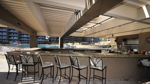 Un espace bar avec vue sur la piscine, des places assises en plein air et un coin cuisine.