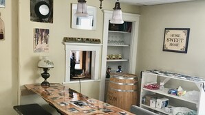 A dining area with a long wooden table covered with photos, a bench, and a vintage lamp. - Brookside House-Large, charming Historic Home. Pet Friendly! (Greenwood)