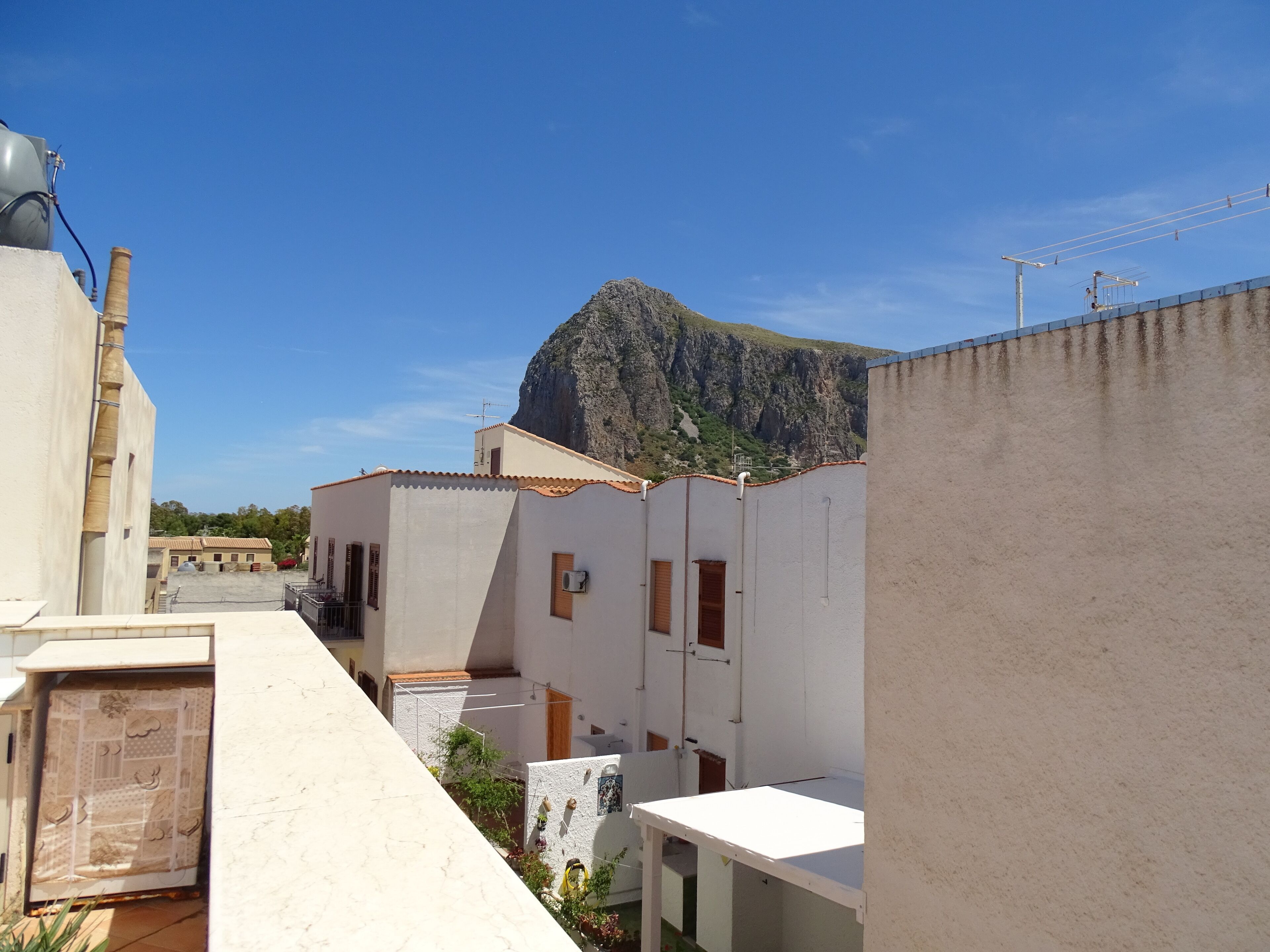 A residential area with buildings, a mountain, and a clear sky.