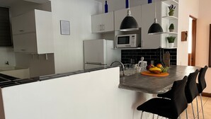 Een moderne keuken met witte kasten, een magnetron en een fruitschaal op het eiland.
