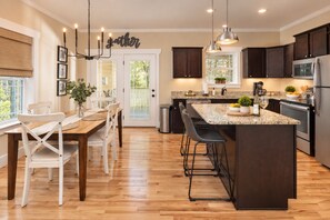 A modern kitchen with dark wood cabinets, a central island with bar stools, and pendant lighting.