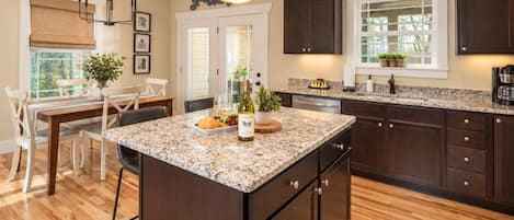 A kitchen with dark wood cabinets, a granite countertop, and a dining area with a table and chairs.