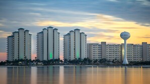 A high-rise hotel with multiple floors and a distinctive tower structure in the foreground. - Summerwind West #202 Oceanfront Condo - Free Beach Chairs & Umbrella. (Navarre Beach)