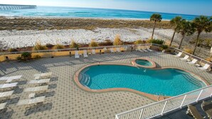 A pool area with lounge chairs and a view of the beach and ocean. - Summerwind West #202 Oceanfront Condo - Free Beach Chairs & Umbrella. (Navarre Beach)