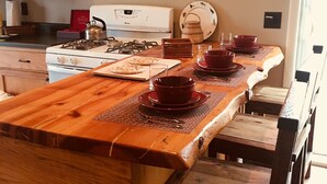Una cocina con armarios de madera, una estufa a gas y una mesa de comedor con platos y cuencos rojos.