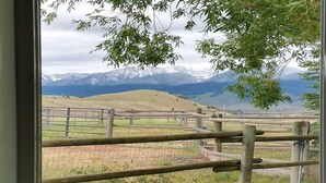 Vista a través de una ventana con una valla de madera y un paisaje montañoso al fondo.