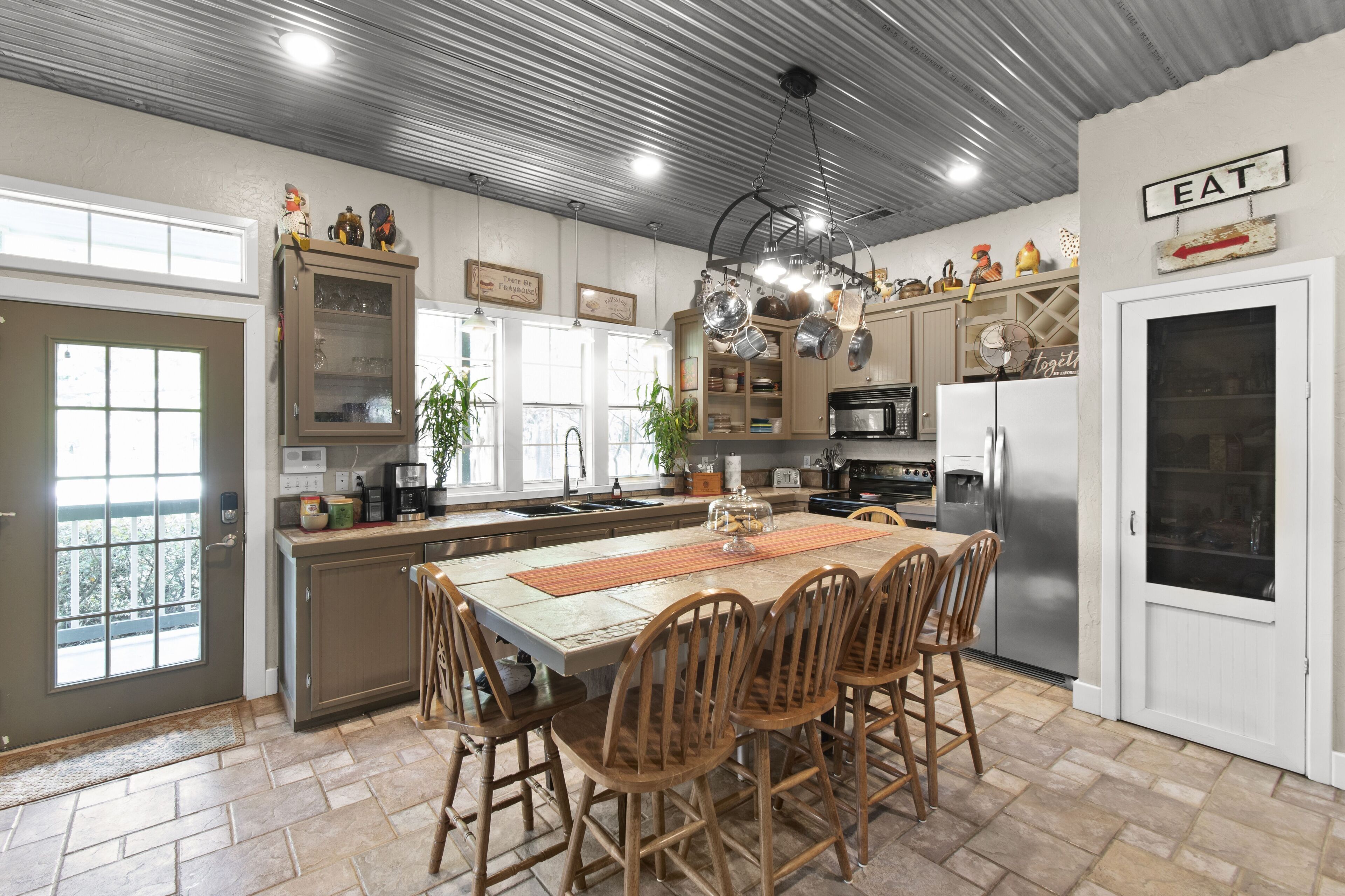 Una cocina con una isla central, sillas de madera y un refrigerador.