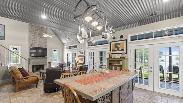 A spacious living area with a stone fireplace, a large island with bar stools, and a television mounted on the wall.