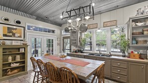 A spacious kitchen with a large island, wooden chairs, and a hanging pot rack.
