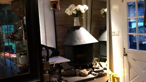 A cozy room with a wood-burning stove, a white door, and a mirror reflecting part of the room. - Cozy designer Cottage on private historic estate-near NYC-Oasis in Metropolis (West Caldwell)