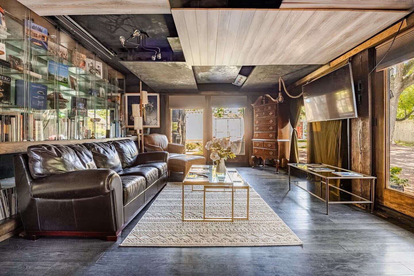 Una sala de estar moderna con un sofá de cuero, una mesa de centro y una estantería llena de libros.