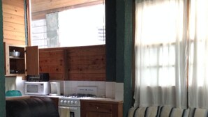 A compact living space with a kitchenette, a sofa, a dining table, and a ceiling fan. - Chippewa Village Pool Apt  (Negril)