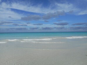 A beach with clear turquoise water and a sandy shore. - Chippewa Village Pool Apt  (Negril)