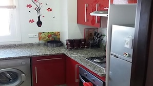 A compact kitchen with a washing machine, a stove, and a refrigerator. - Great Pool View Apartment in Kariat Cabo 4548 (Cabo Negro)