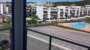 A view of a residential area with modern apartment buildings, a parking lot, and a swimming pool. - Great Pool View Apartment in Kariat Cabo 4548 (Cabo Negro)