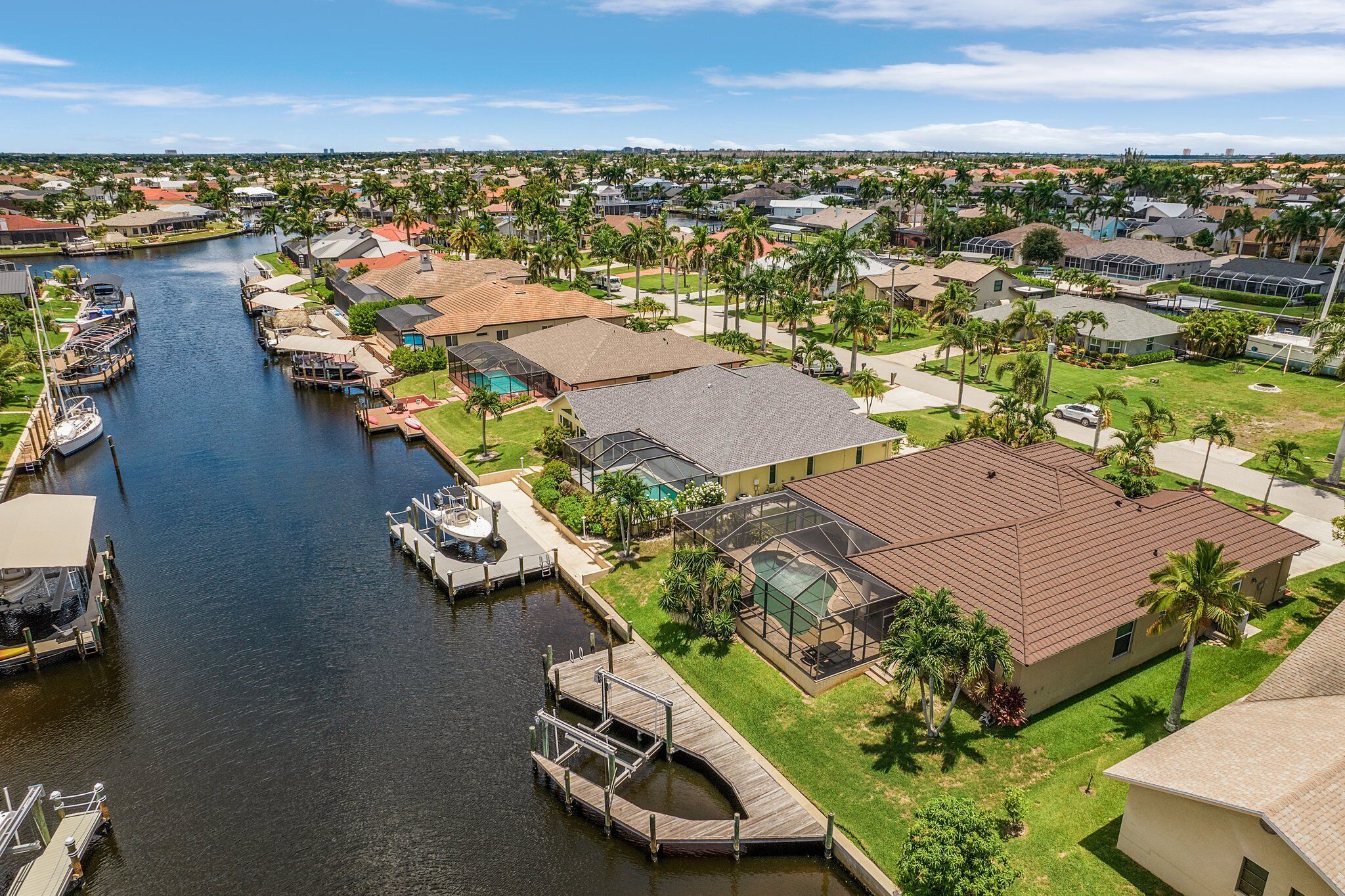 A residential area with a canal, houses, and a dock with boats.