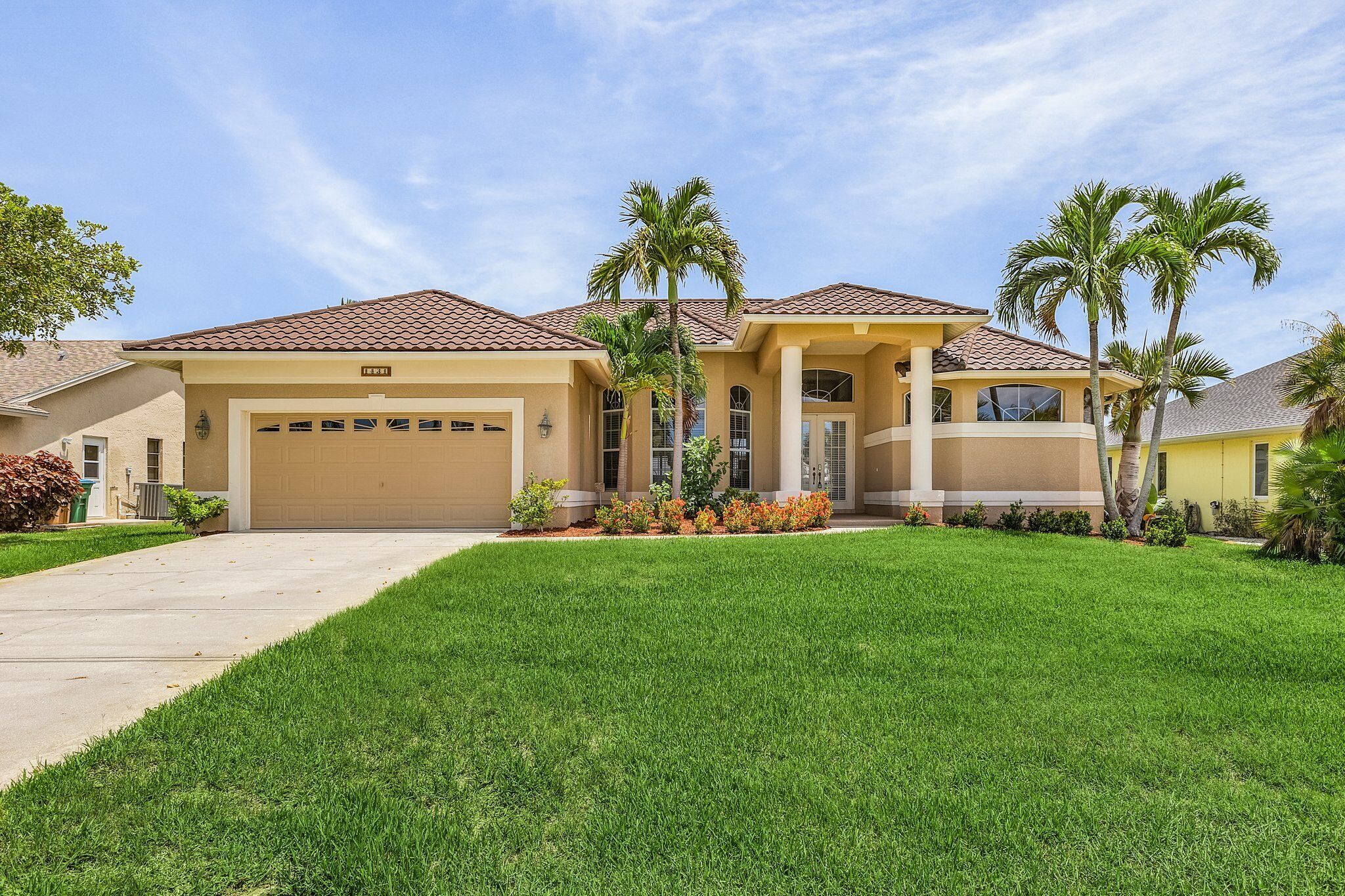 A two-story house with a garage, a covered patio, and a well-maintained lawn.