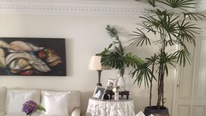 A living room with a sofa, armchair, coffee table, and a small side table with a lamp and decorative items.