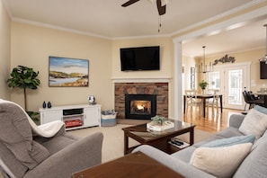 A living room with a fireplace, a television, and a dining area in the background.