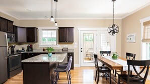 A modern kitchen with dark wood cabinets, a granite countertop, and a central island with bar stools.